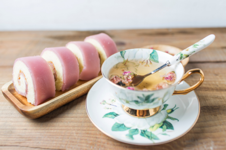 A pink swiss roll and a cup of tea in a pretty saucer